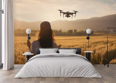 Woman in a field at sunset, operating a drone, which symbolizes modern agricultural technology and innovation. Wall mural