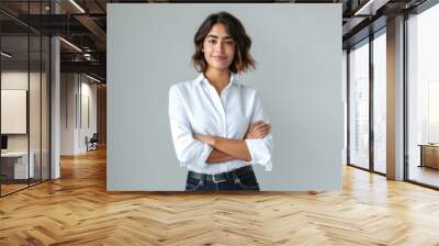 woman with short blonde hair and a confident smile is wearing a white shirt and stands with her arms crossed against a light grey background Wall mural