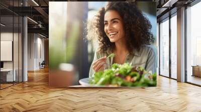 Young athletic woman eats a salad in her plate while eating breakfast Wall mural