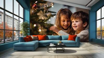 Young children decorate the Christmas tree at home. Wall mural