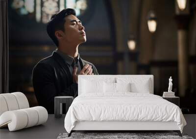 Young man praying in a church. Wall mural