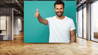 Young man standing over isolated blue background doing happy thumbs up gesture with hand. Wall mural