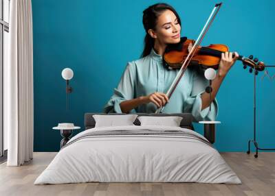 Young woman playing violin on blue background Wall mural