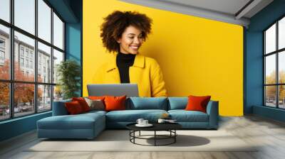 Young woman working on a laptop on a yellow background. Wall mural