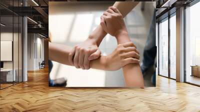 3 people are laying their hands together. They catch the wrist in a triangle in the daytime in Bangkok, Thailand. Concept, unity and collaboration Wall mural