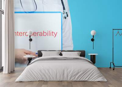 Interoperability. Doctor with stethoscope holds blue clipboard. Text is written on document. Wall mural