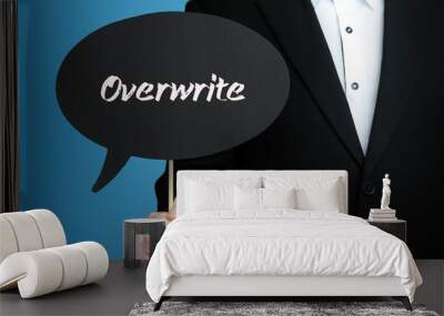 Overwrite. Businessman in suit holds speech bubble at camera. The term Overwrite is in the sign. Symbol for business, finance, statistics, analysis, economy Wall mural