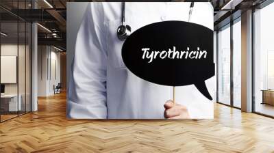 Tyrothricin. Doctor in smock holds up speech bubble. The term Tyrothricin is in the sign. Symbol of illness, health, medicine Wall mural