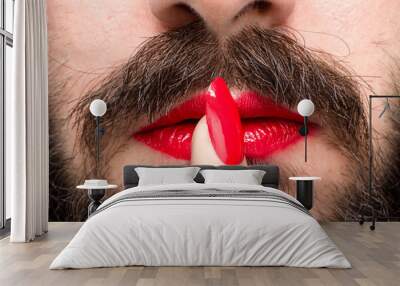 Bearded Man with Red Lipstick on His Lips and Nail Polish Making Silence Gesture Wall mural