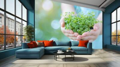 Young girl holding a heart-shaped plant, symbolizing heart health and nature conservation for World Heart Day celebration. Wall mural