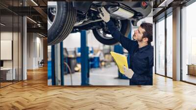 Auto car repair service center. Mechanic examining car Wall mural