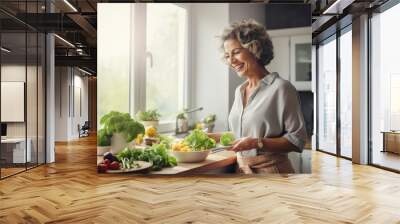 Happy middle-aged woman preparing a meal in the kitchen Wall mural