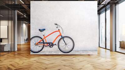 Orange color city bike against the wall with shiny silvery metallic plaster. Summertime concept Wall mural