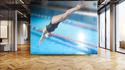 Female swimmer, that jumping into indoor swimming pool. Wall mural