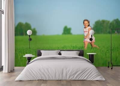 Young happy girl running at green wheat field Wall mural