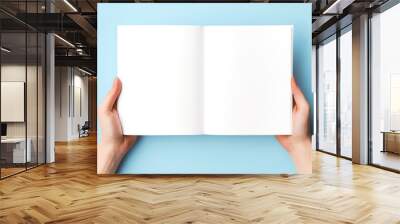 female hands holding book blank paper pages mockup on light blue background Wall mural