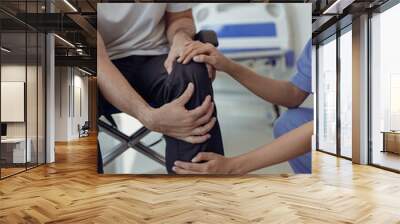 A young female doctor is caring for a man in a wheelchair in the house. Positive and happy Asian female nurse or physical therapist in blue uniform caring for male patient in close proximity. Wall mural