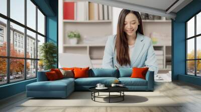 Asian businesswoman working using a laptop computer Marketing report with calculator document on table Plan to analyze financial reports Wall mural