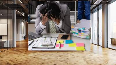 Young Asian accountant, office worker working with documents, tired and stressed, hands covering face, sitting at table in office with coworkers bringing documents. Wall mural