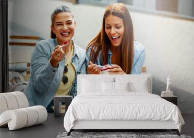 Two female friends having fun eating cheesecake outdoors Wall mural