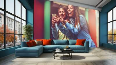 Two young women using smartphone in the street Wall mural