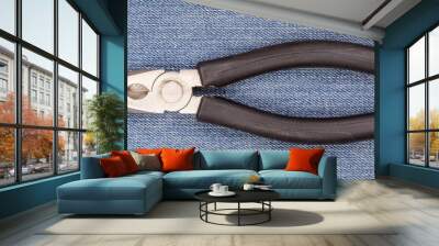 Pliers black handle tool isolated on blue jeans background Wall mural