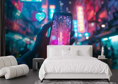 hand holding a smartphone in a busy street with neon lights at night. Wall mural