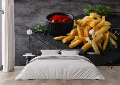 Homemade baked french fries with ketchup and rosemary on a black slate board Wall mural