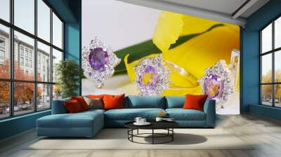 Beautiful gold ring and earrings with gemstones on a yellow flower. Wall mural