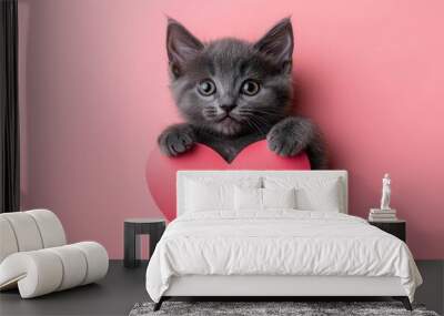 gray kitten crawls out of a heart on a pink background Wall mural