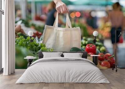 a persons hand holding empty cotton tote bag at farmers market Wall mural