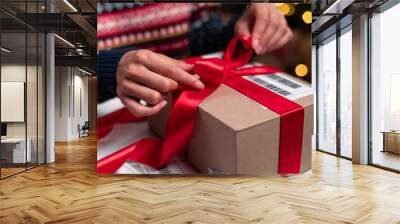 Merry Christmas shipping delivery concept. Santa Claus packing present box wrapping gift with red ribbon preparing post shipping delivery parcel. Wall mural