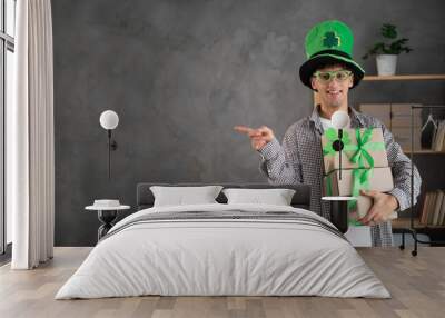 St. patrick's day sale, young man in leprechaun hat holding delivery boxes and pointing finger at advertising space Wall mural