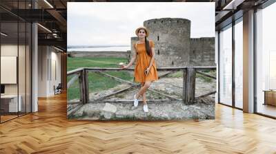 Woman tourist in orange dress near ancient fortress Wall mural