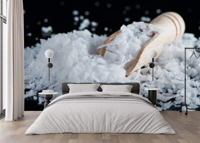 Salt flakes and wooden scoop on black background Wall mural