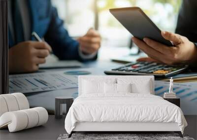 A businessman is writing with a pen on a piece of paper with a lot of numbers and graphs Wall mural