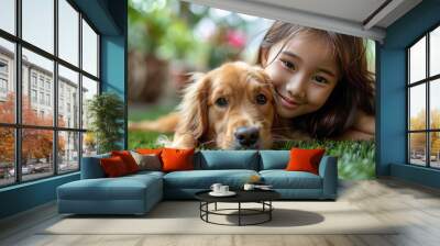 An Asian girl is playing with a puppy on the green artificial lawn in her yard. Wall mural