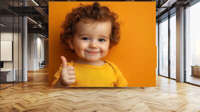 Adorable baby boy showing thumb up on orange background. Happy child with curly hair. A smiling toddler giving a thumbs up with generative ai Wall mural