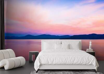 Wide background panorama of a brilliant colorful sky reflecting off water at sunset Wall mural