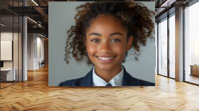 A young woman with curly hair is smiling at the camera. Wall mural