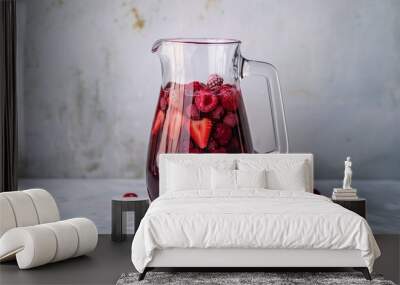 A clear pitcher of mixed berry juice with visible berries inside, set against a minimalist backdrop Wall mural