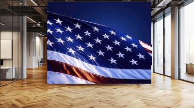 A close-up of the American flag, its stars and stripes illuminated against a deep blue sky, creating a powerful image of freedom and unity. Wall mural