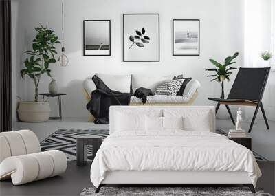 Black and white geometric print rug on the floor of a modern living room with a wooden sofa, black chair, posters in frames, planters and a blanket on it Wall mural