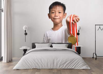 Asian boy showing his gold medal towards the camera isolated on a white background. The child celebrating his victory Wall mural