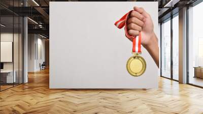 Hand holding gold medal isolated on white background. The winner and successful concept Wall mural