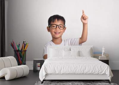 Portrait of an Asian boy studying isolated on a white background. Raising his hand to answer a question Wall mural