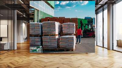 Stacked packages with construction materials near the warehouse. Forklift loader is working Wall mural