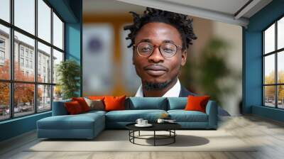 A young man with dreadlocks is wearing glasses and posing for a portrait in an office setting Wall mural