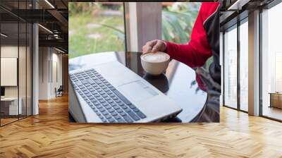 Casual man working with laptop and drinking coffee in coffee shop Wall mural