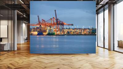 International cargo ship with containers cargo illumination and gantry cranes at port Wall mural